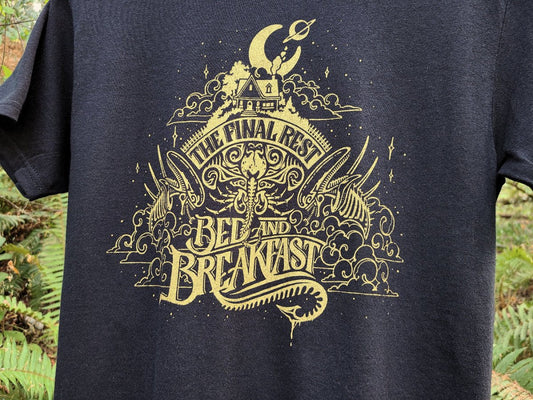 Black t-shirt with gold graphic design featuring an Alien scifi design, against a natural background.