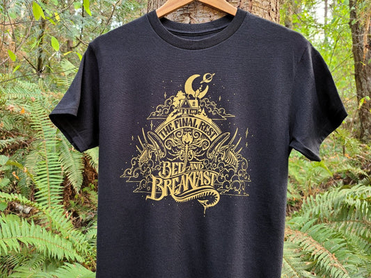 Black t-shirt with gold Alien graphic design hanging on a wooden hanger against a forest background
