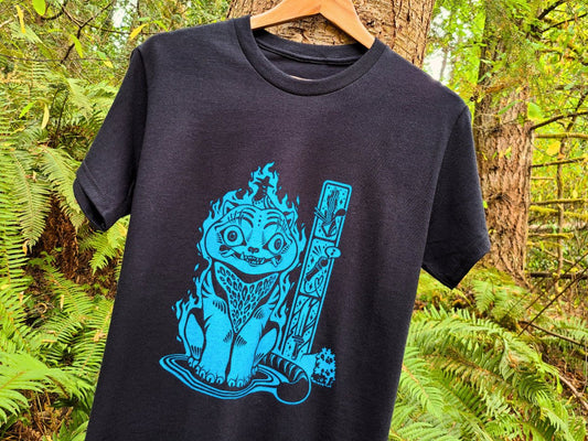 Black t-shirt with blue graphic design Derpy Tiger, hanging on a tree branch in a forest setting.