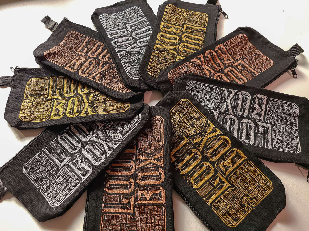 A set of black canvas zippered pouches arranged in a circular pattern, each featuring a distressed, stylized 'LOOT BOX' graphic in different colors including gold, Copper, and silver.
