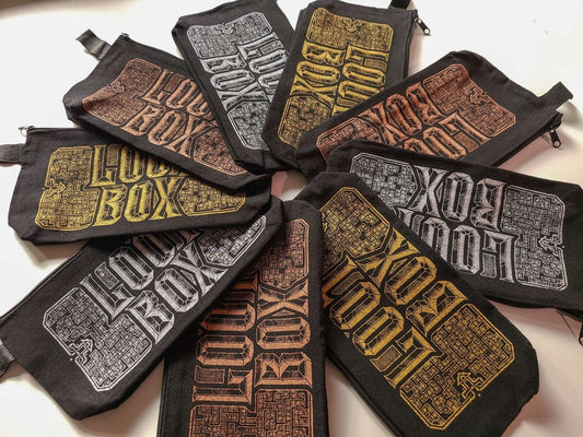 A set of black canvas zippered pouches arranged in a circular pattern, each featuring a distressed, stylized 'LOOT BOX' graphic in different colors including gold, Copper, and silver.