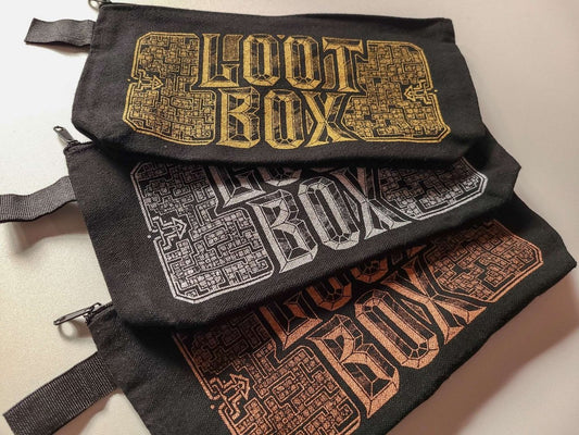 Three black canvas pouches stacked diagonally, each featuring a different colored 'LOOT BOX' graphic in gold, silver, and copper. The pouches have zipper closures and webbing straps on the sides.