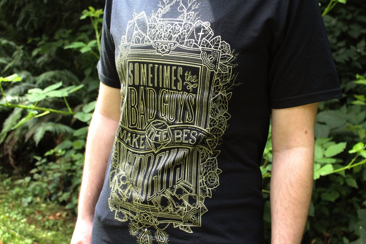 Person wearing a black t-shirt with a graphic design and text in an outdoor setting